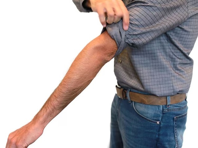 Mann zeigt wie man sich den Hemdärmel im Casual Look krempelt.