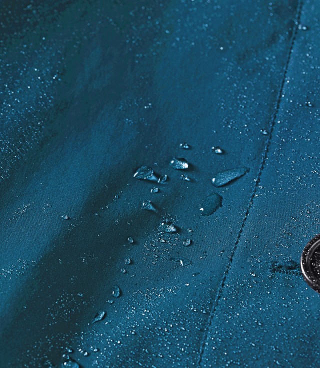 Nahaufnahme von blauem, wasserabweisendem Stoff mit Wassertropfen darauf.