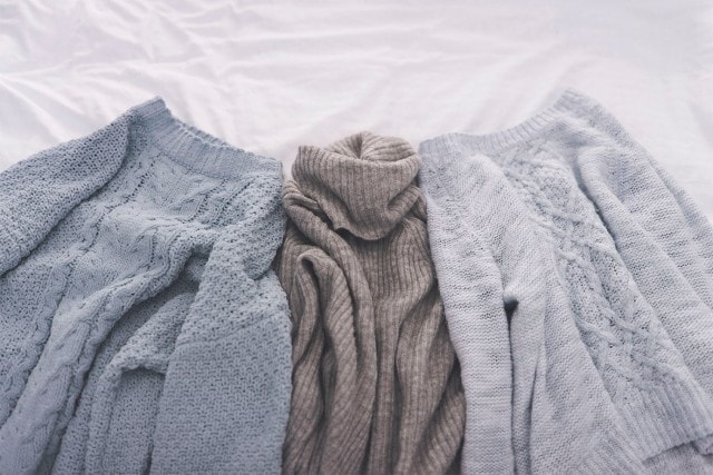 Drei liegende verschieden farbige Pullover aus Wolle.