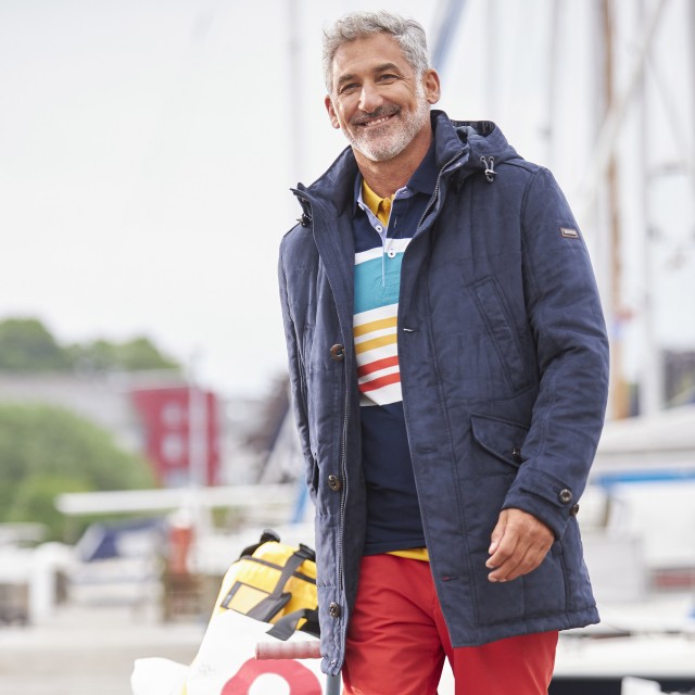 Mann in einer wasserabweisenden Jacke steht in Nieselregen.