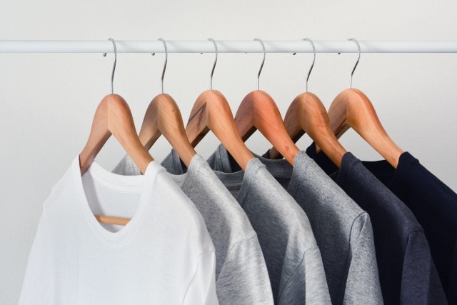 Kleiderstange mit mehreren Shirts jeweils auf einem Kleiderbügel.