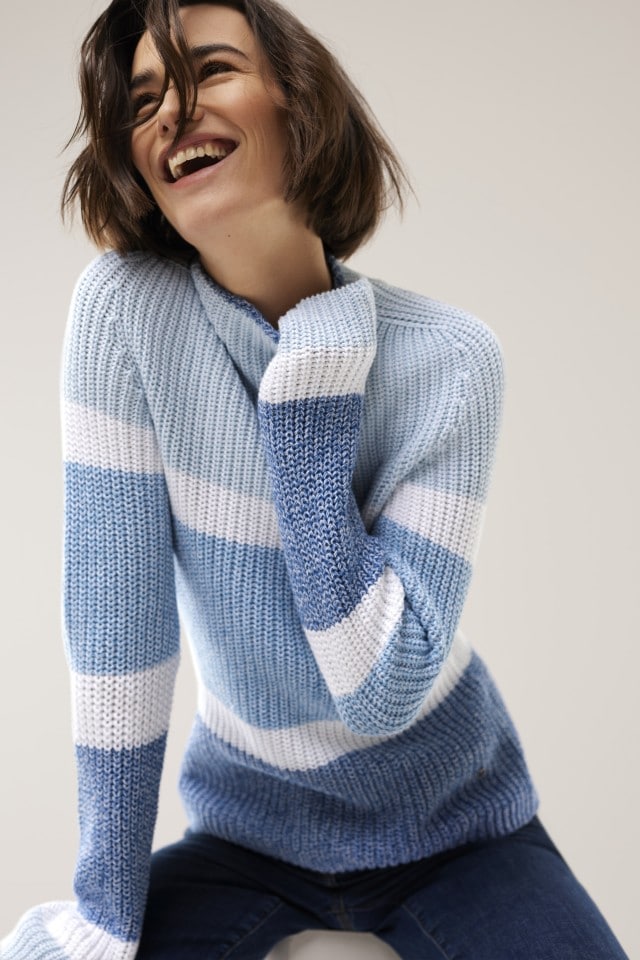 Frau in blau-weiß gestreiftem Pullover lacht  fröhlich.