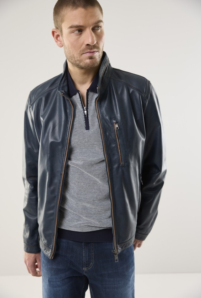 Mann in navyblauer Lederjacke, gestreiftem Pullover und Jeans.