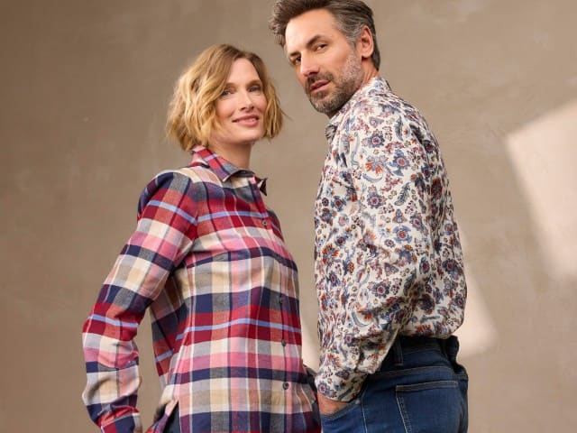 Zwei Personen tragen gemusterte Hemden – eine im karierter Stil, die andere mit floralem Muster. Beide Outfits wirken lässig, farbenfroh und modern kombiniert. Zwei Personen tragen gemusterte Hemden – eine im karierter Stil, die andere mit floralem Muster. Beide Outfits wirken lässig, farbenfroh und modern kombiniert.