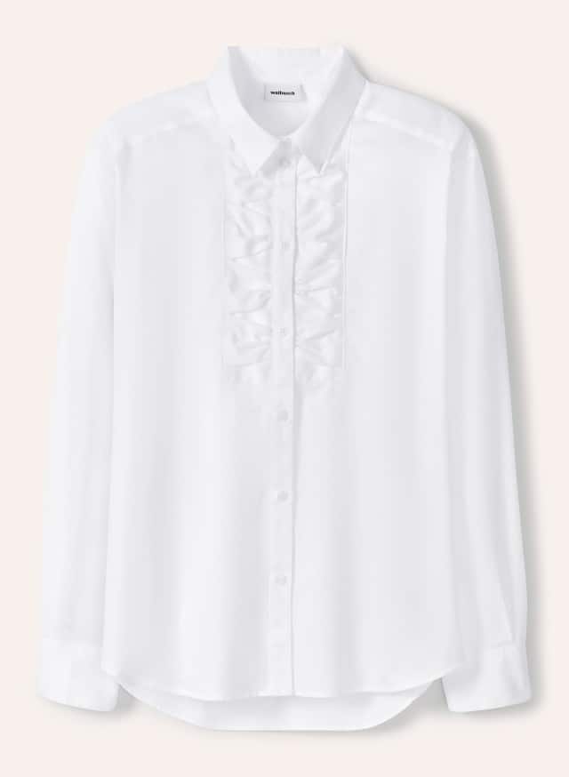 Eine weiße Bluse mit Knopfleiste und dekorativen Rüschen auf der Vorderseite liegt flach ausgebreitet vor hellem Hintergrund. Eine weiße Bluse mit Knopfleiste und dekorativen Rüschen auf der Vorderseite liegt flach ausgebreitet vor hellem Hintergrund.