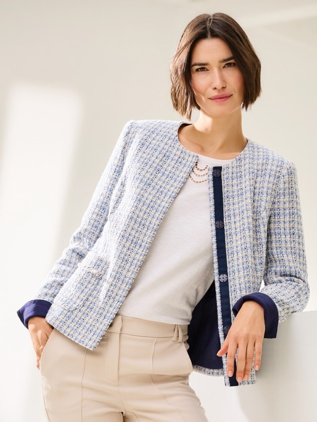 Frau trägt weißes Shirt unter einem hellblauen Blazer und einer Hose in beige