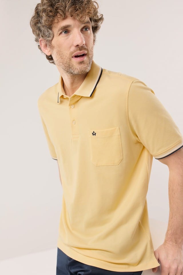 Ein Mann trägt ein Extraglatt-Polo Bicolor in Uni Gelb.
