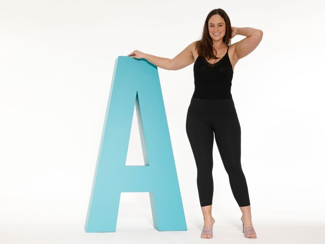Dame steht neben einem großen blauen A-Buchstaben.