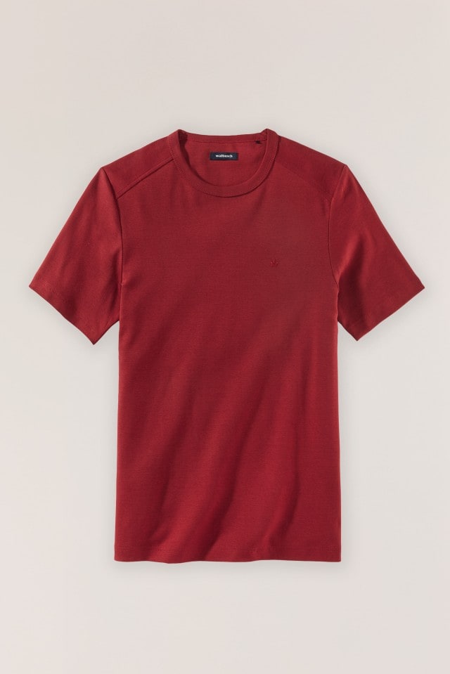 Ein schlichtes, bordeauxrotes T-Shirt mit Rundhalsausschnitt liegt vor einem neutralen Hintergrund.