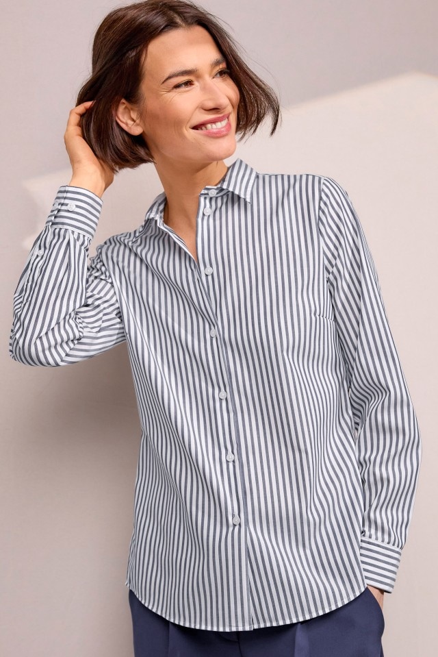 Eine Person trägt eine weiß-blau gestreifte Bluse mit langen Ärmeln und weißen Knöpfen.