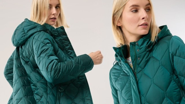 Eine Frau trägt eine gesteppt-grüne Winterjacke mit Kapuze und Reißverschluss. Der Look wirkt modern, sportlich und zugleich alltagstauglich.