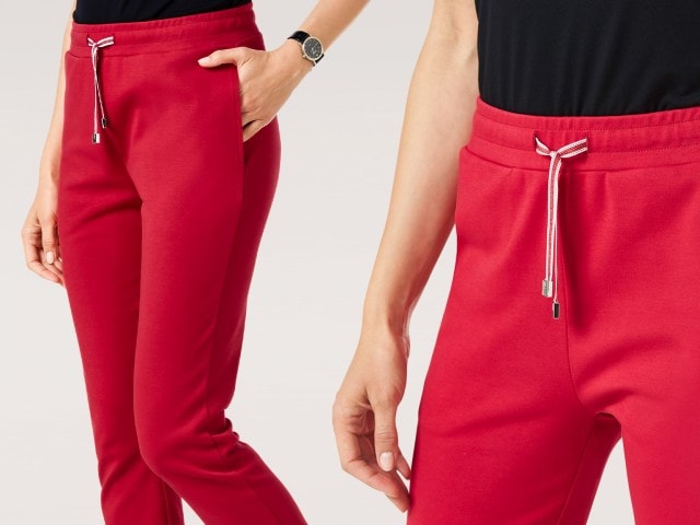 Eine Frau trägt eine schmal geschnittene rote Jogpants mit Kordelzug. Der Look wirkt sportlich und modern-lässig.