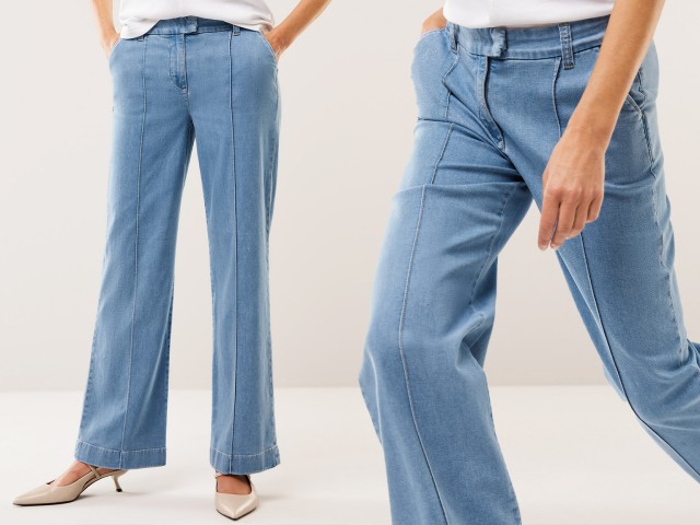 Eine Frau trägt eine hellblaue, weit geschnittene Jeans mit markanten Nähten. Kombiniert mit beigen Absatzschuhen wirkt der Look modern und lässig-elegant.