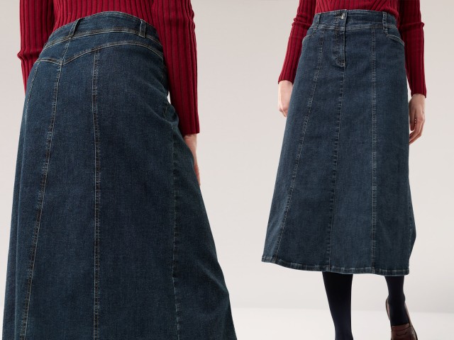 Eine Frau trägt einen dunkelblauen Jeansrock in A-Linie mit sichtbaren Nähten. Kombiniert mit einem roten Strickoberteil entsteht ein klassisch-lässiger Look.
