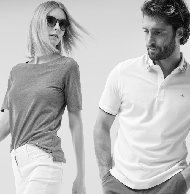 Eine Frau mit Sonnenbrille trägt ein einfarbiges T-Shirt und Mann trägt ein kurzärmliges, helles Poloshirt; beide schauen zur  Seite.