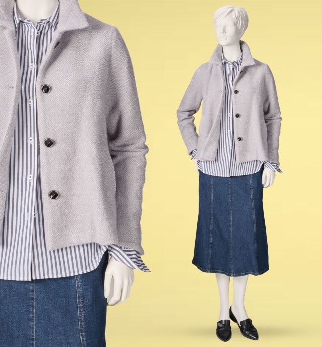 Eine Schaufensterpuppe trägt eine hellgraue Jacke über einer blau-weiß gestreiften Bluse. Dazu kombiniert sind ein jeansblauer Rock und schwarze Slipper für einen klassischen, gepflegten Look.