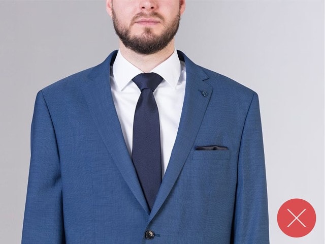 Mann trägt einen blauen Anzug, mit einer blauen Krawatte und einem weißen Hemd.