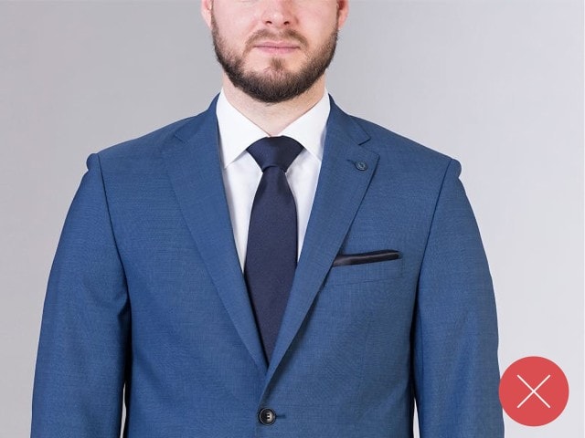 Mann trägt einen blauen Anzug, mit einer blauen Krawatte und einem weißen Hemd.