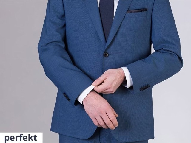 Mann in einem blauen Anzug hält eine Hand ans Ende des Ärmels.