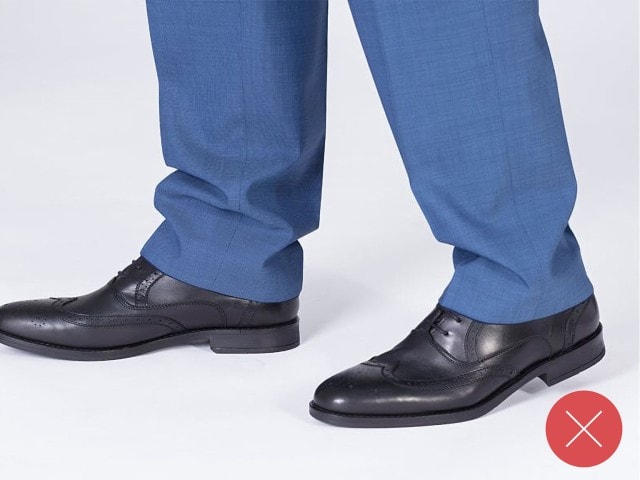 Bildausschnitt einer blauen Anzughose mit schwarzen Anzugschuhen.