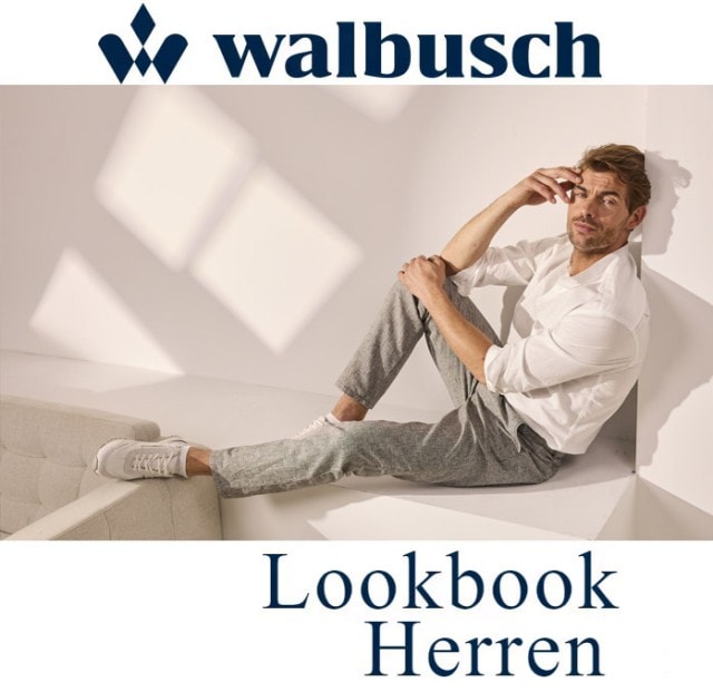 Ein männliches Walbusch Model mit weißem Hemd sitzt an einer Wand