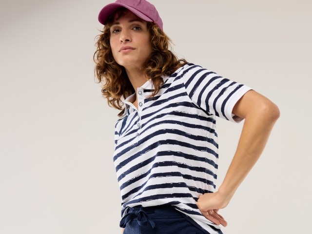 Frau trägt ein gestreiftes Poloshirt dazu eine rote Cap.