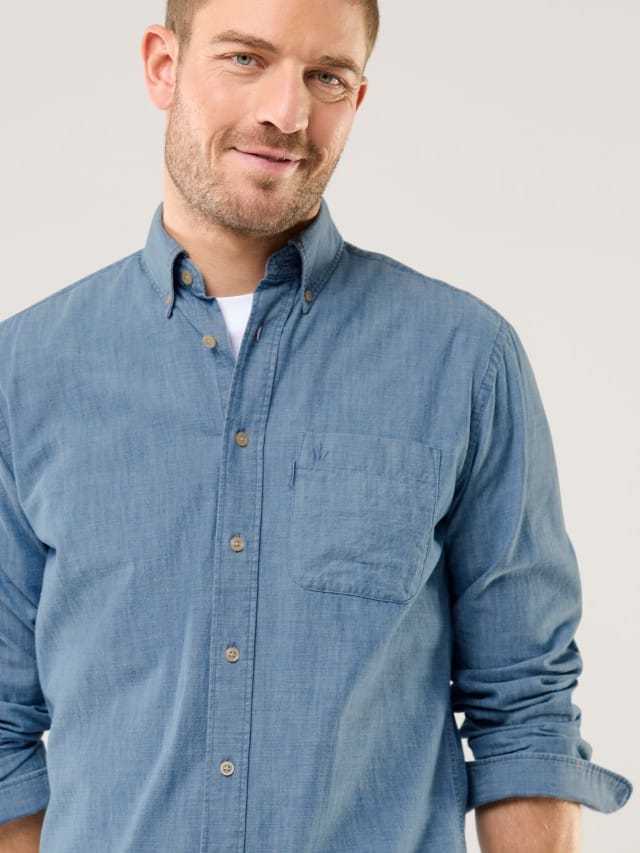 Ein Mann trägt ein blaues Hemd, darunter ein Shirt in Weiß.