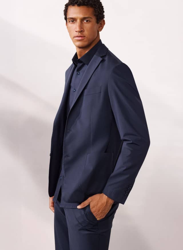 Ein Mann trägt einen Travel Anzug in Marine mit passendem Hemd.