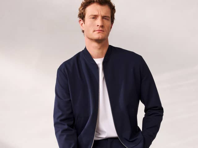 Ein Mann trägt ein Blouson mit Stehkragen in Marine, darunter ein weißes Shirt.