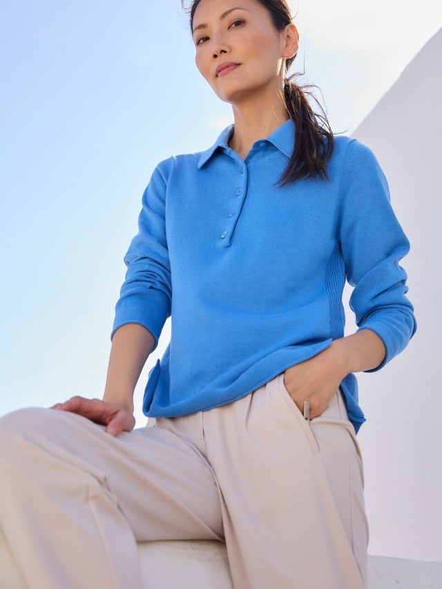 Eine Frau trägt einen leuchtend blauen Pullover zu einer hellen, locker fallenden Hose, was frisch, modern und entspannt wirkt.