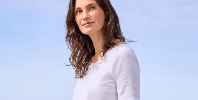 Eine Frau trägt ein schlichtes, weißes T-Shirt. Das Outfit wirkt minimalistisch und zeitlos.