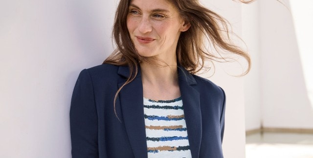 Eine Frau trägt einen Blazer in Marine, darunter ein gestreiftes Shirt.