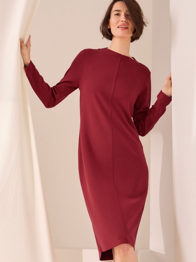 Eine Frau trägt ein rotes Langarm-Kleid aus Jersey.