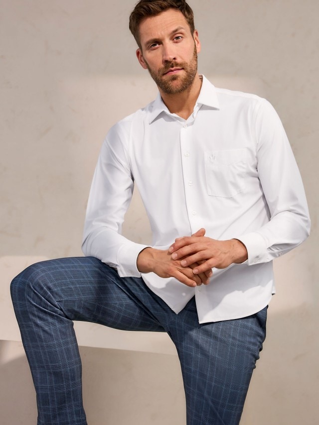 Ein Mann trägt ein weißes Hemd, dazu eine karierte Chino.