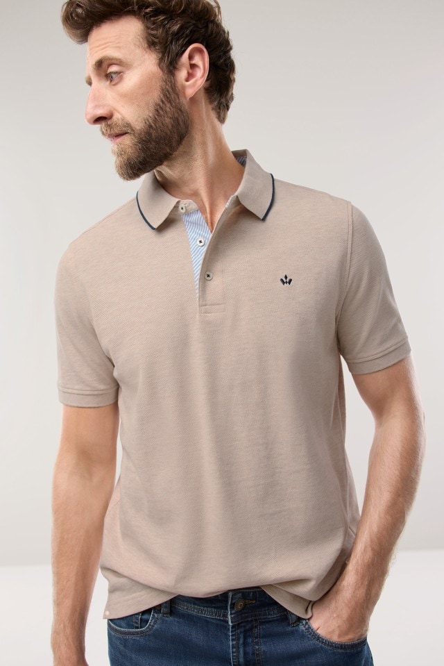 Ein Mann trägt ein Polo-Shirt in der Farbe Natur, dazu eine Jeans.