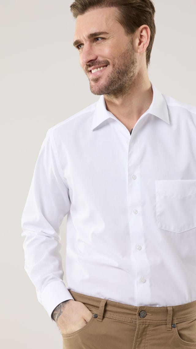 Ein Mann trägt ein weißes Hemd, dazu eine Hose in Beige.