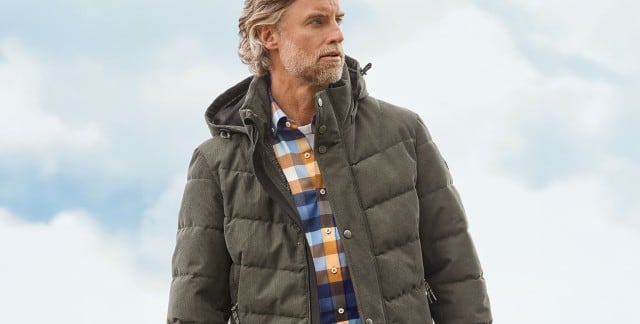 Ein Mann trägt eine gesteppte, olivgrüne Winterjacke über einem karierten Hemd in Blau-, Weiß- und Brauntönen; der Look wirkt lässig und herbstlich. Ein Mann trägt eine gesteppte, olivgrüne Winterjacke über einem karierten Hemd in Blau-, Weiß- und Brauntönen; der Look wirkt lässig und herbstlich.