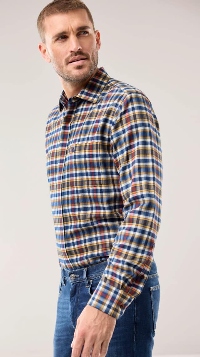 Eine Person trägt ein bunt kariertes Hemd in Blau-, Gelb- und Rottönen, kombiniert mit einer blauen Jeans für einen lässigen Alltagslook.
