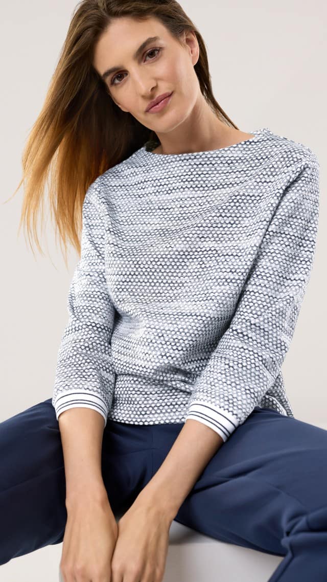 Eine Frau trägt ein Struktur Jersey Sweatshirt in Marine, dazu eine passende Hose.
