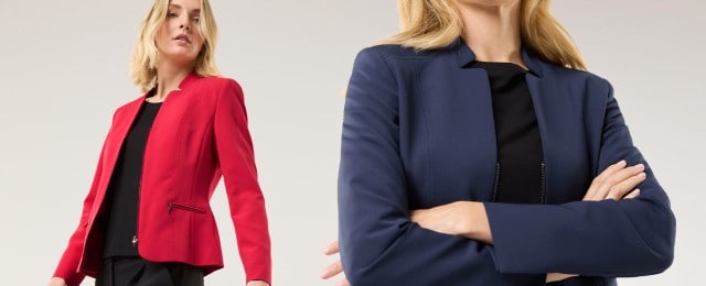 Zwei Frauen tragen schlichte, elegante Blazer: eine in Rot, die andere in Dunkelblau. Beide kombinieren die Blazer mit einem schwarzen Oberteil und wirken modern und professionell.