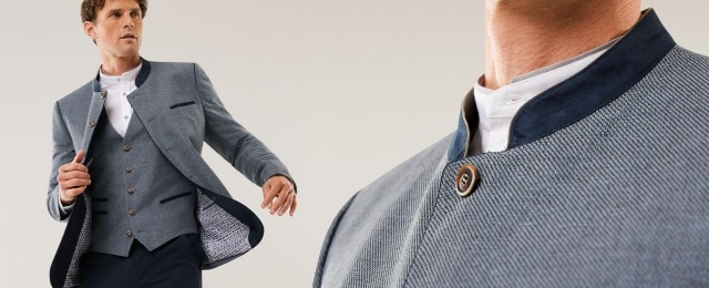 Ein Mann trägt ein elegantes, hellblau gemustertes Sakko mit Stehkragen, dazu eine passende Weste und ein weißes Hemd ohne Krawatte. Der Look ist stilvoll und modern, inspiriert von traditionellen Elementen.