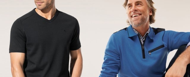Zwei Männer präsentieren moderne Freizeitmode: Einer trägt ein schlichtes, schwarzes T-Shirt mit V-Ausschnitt, der andere einen blauen Pullover mit Reißverschluss und auffälligen schwarzen Details über einem gemusterten Hemd. Beide Looks wirken sportlich und stilvoll.