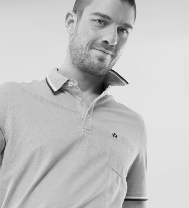 Ein Mann trägt ein Poloshirt und lächelt.