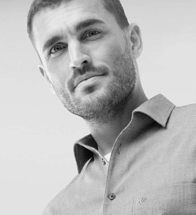 Ein Mann trägt ein Hemd, darunter ein weißes Shirt.