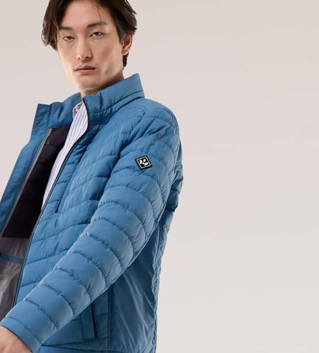 Ein Mann trägt eine Steppjacke in Blau, darunter ein gestreiftes weißes Hemd.