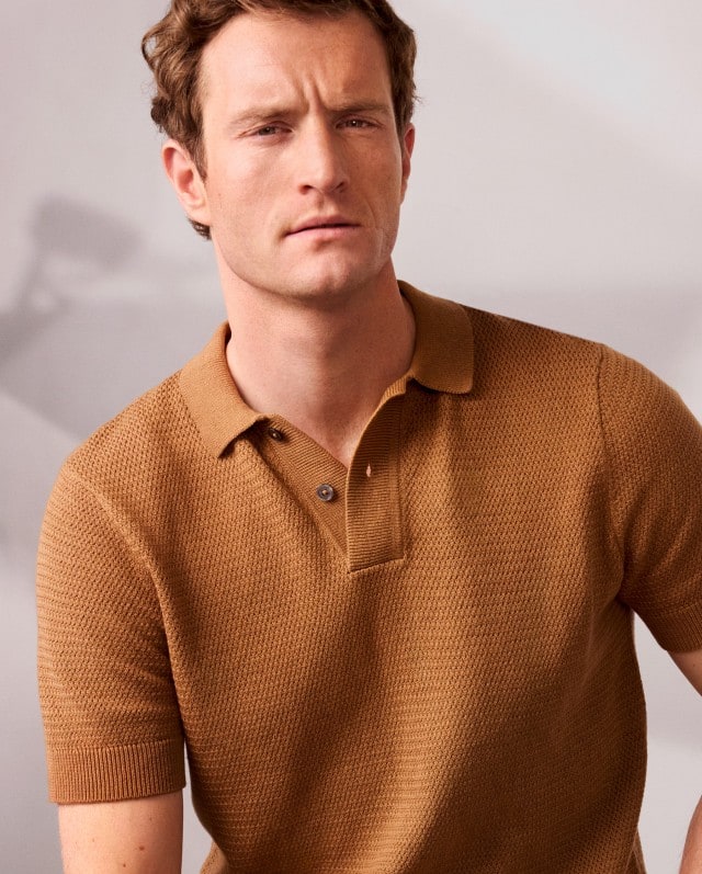 Ein Mann trägt ein Kurzarm Polo-Shirt in einem Braunton. 