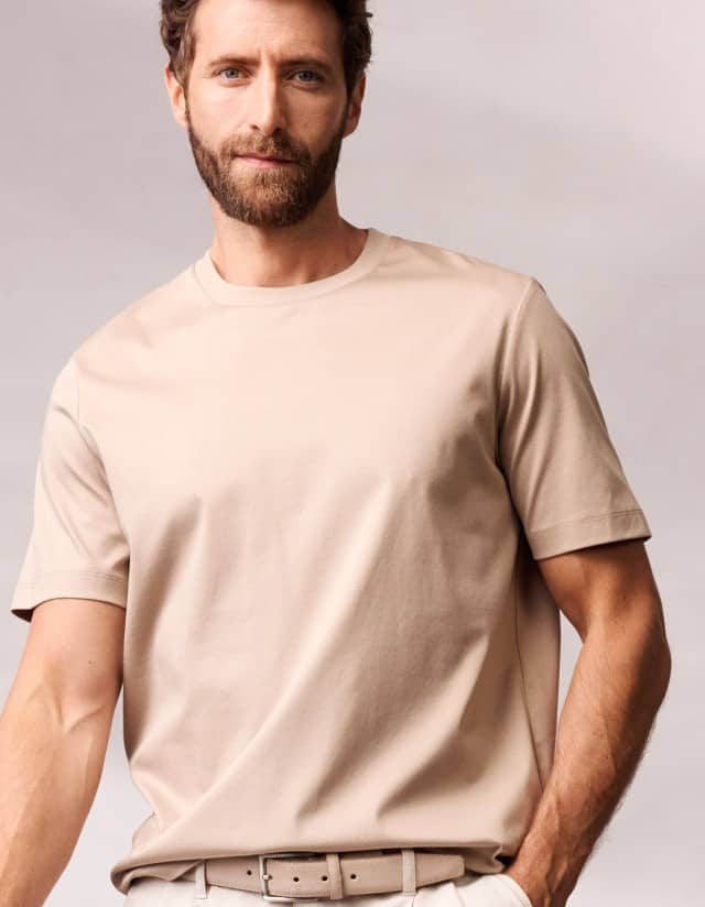 Ein Mann trägt ein T-Shirt in der Farbe Sand.