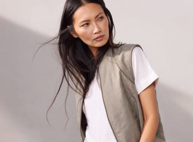 Eine Frau trägt ein weißes Shirt, darüber eine Jacquardweste in Khaki.