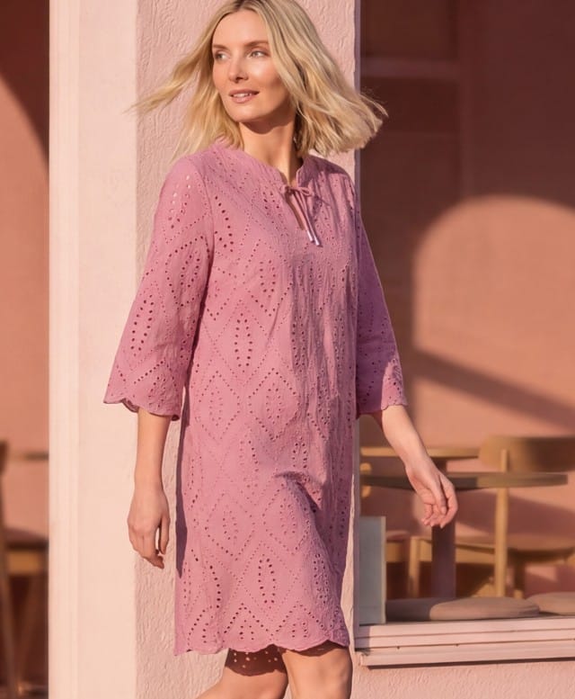 Eine Frau trägt ein Kleid mit Lochstickereien in der Farbe Nelke.