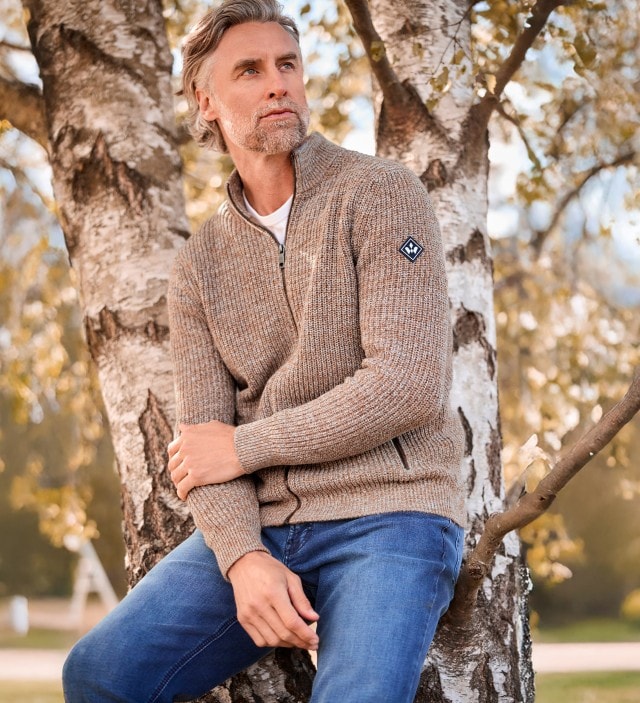 Ein Mann trägt die Mouline Zip-Jacke in Natur, darunter ein weißes Shirt und dazu eine Jeans.